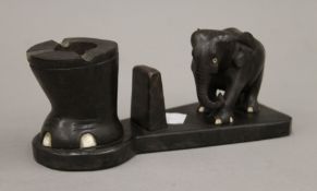 An early 20th century carved ebony and bone smokers compendium surmounted with an elephant.