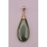 A gold mounted jade pendant. 4 cm high excluding suspension loop.