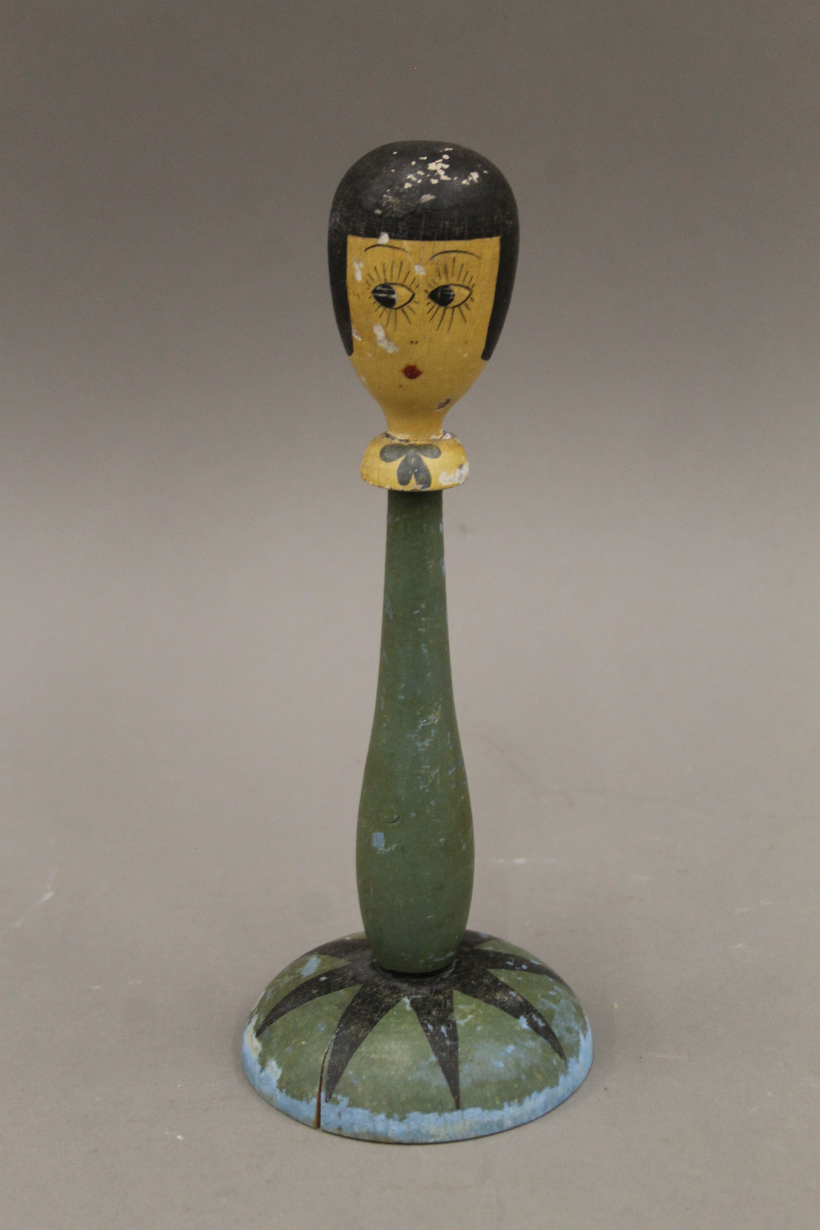 An early 20th century painted wooden display stand of female figural form. 25 cm high.