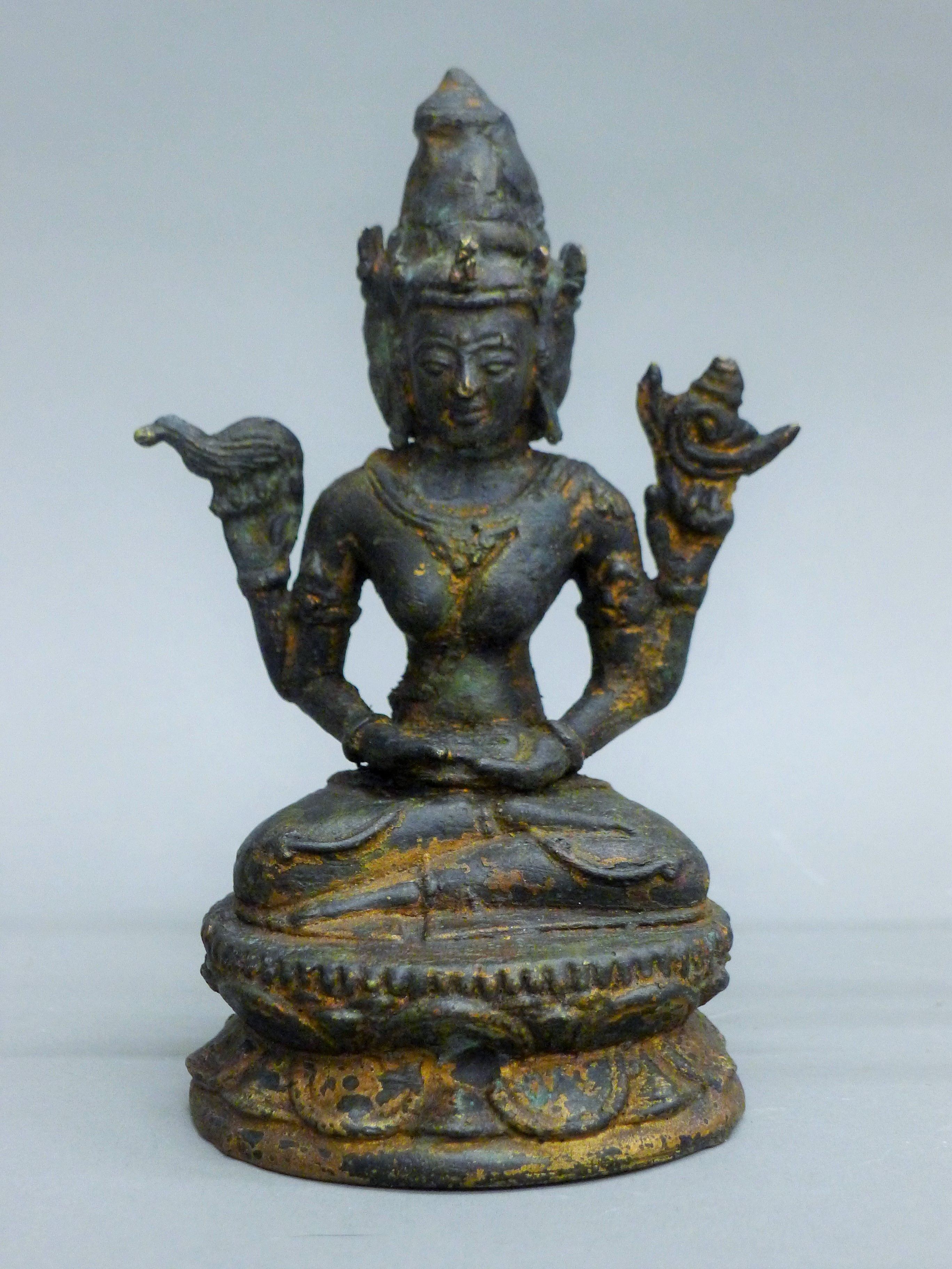 A bronze figure, possibly Ushnishavijaya, seated on a double lotus base. 15.5 cm high.