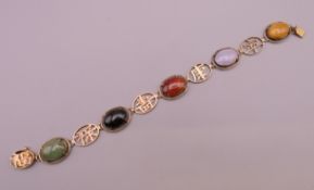 A 14 K gold jade bracelet set with various cabochon stones and Chinese symbols. 18 cm long. 12.