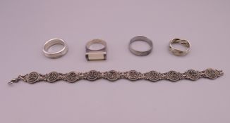 A silver bracelet and four silver rings.