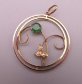 A gold, emerald and seed pearl pendant. 3 cm diameter. 2.2 grammes total weight.