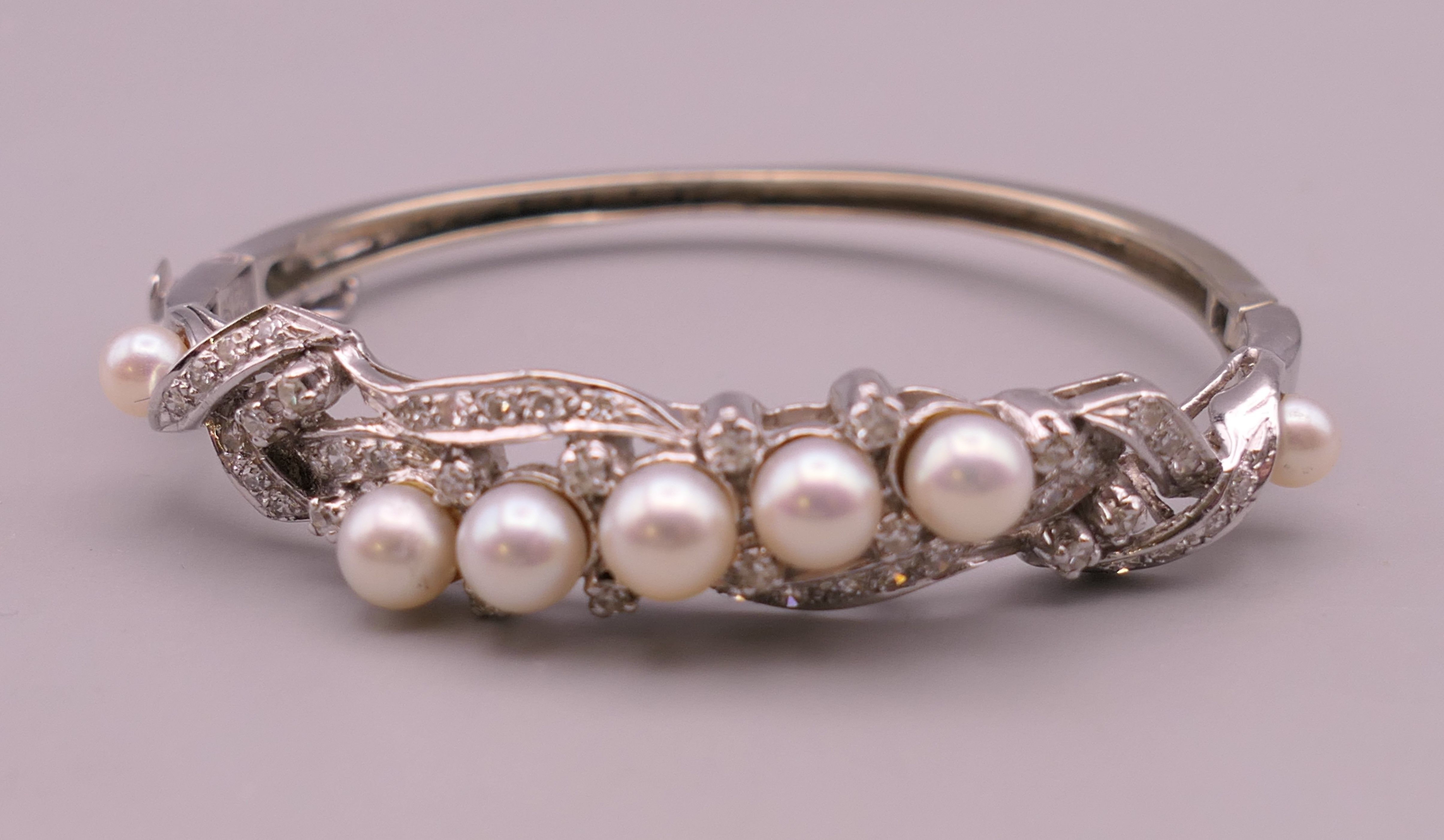 A 14 K white gold diamond and pearl bangle. 5 cm internal diameter. 16.5 grammes total weight.