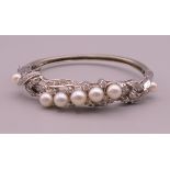 A 14 K white gold diamond and pearl bangle. 5 cm internal diameter. 16.5 grammes total weight.