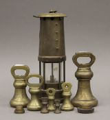 A quantity of brass weights and a miner's lamp.