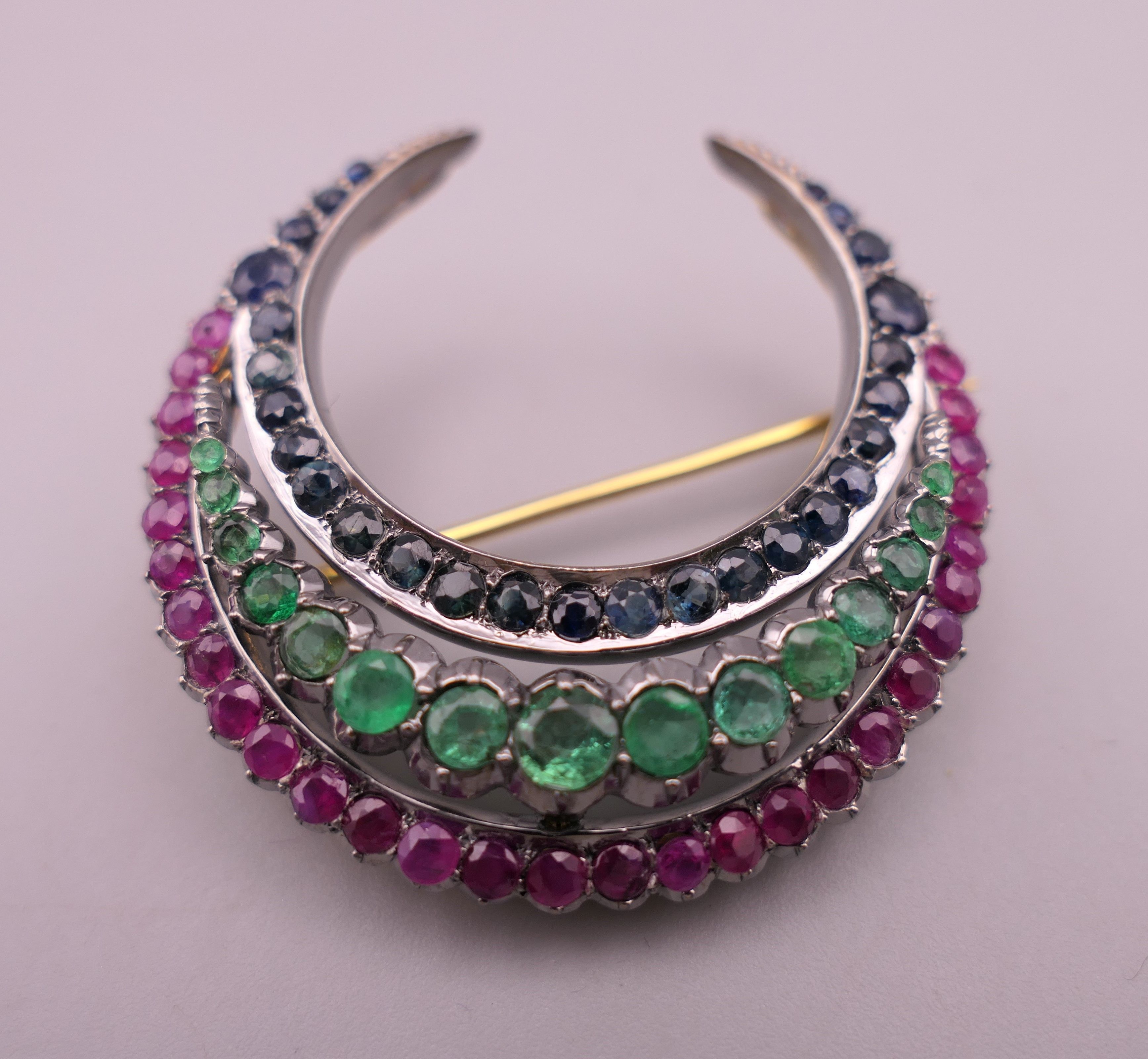 A silver and gold, ruby, emerald and sapphire crescent form brooch. 4 cm wide. - Image 2 of 4