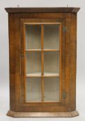 A glazed walnut hanging corner cabinet. 75 cm high.