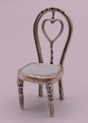 A silver miniature model of a chair. 4.5 cm high.