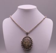 A silver locket on chain. Locket 4.5 cm high excluding suspension loop, chain 76 cm long.