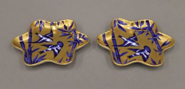 A pair of Coalport gilt heightened blue and white shaped porcelain dishes depicting birds.