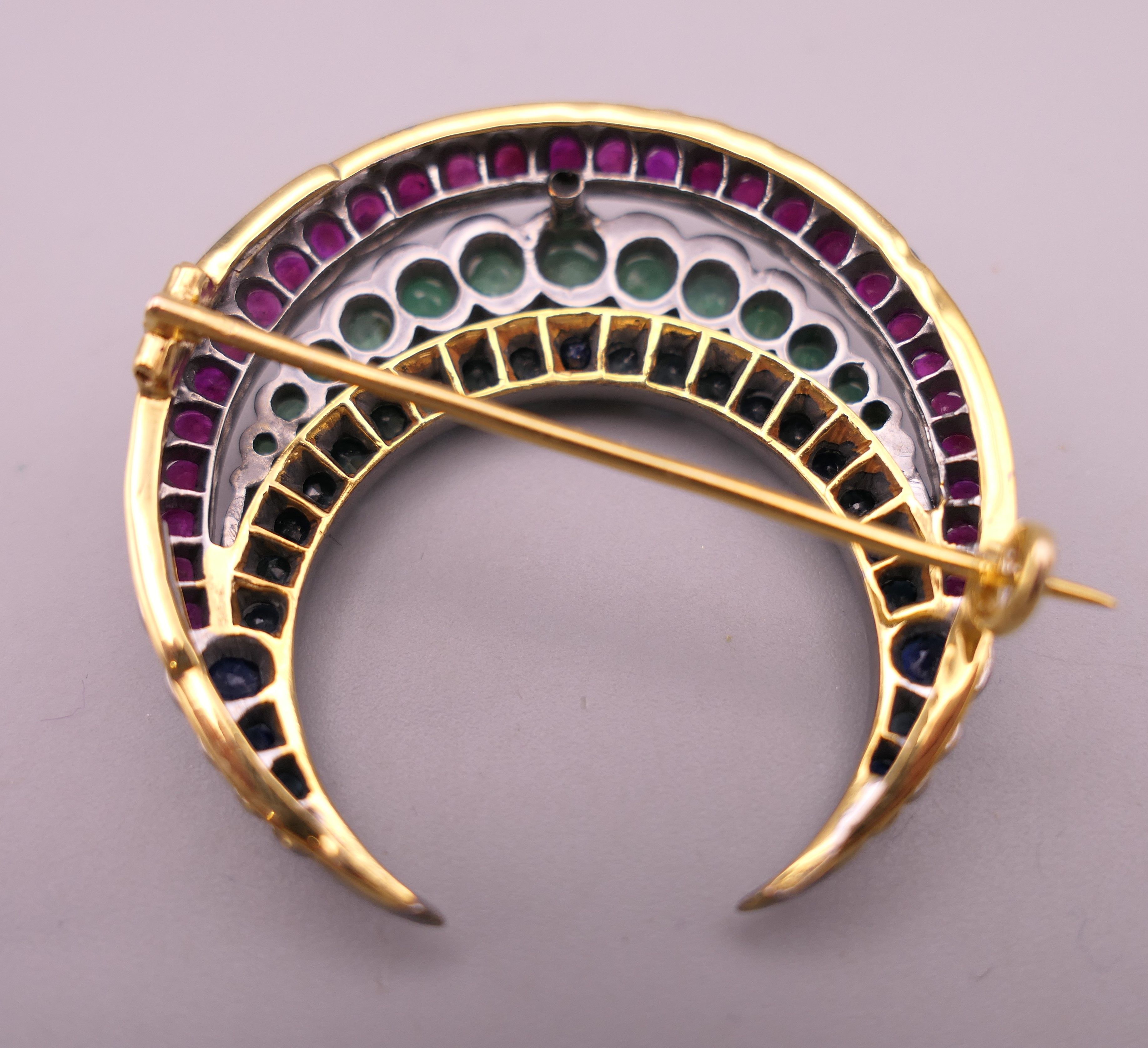 A silver and gold, ruby, emerald and sapphire crescent form brooch. 4 cm wide. - Image 3 of 4