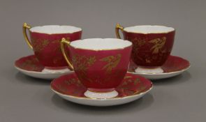 Three gilt decorated Coalport porcelain cups and saucers. The cups 7 cm high.