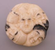 A bone netsuke formed as faces. 4 cm diameter.