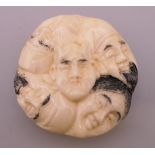 A bone netsuke formed as faces. 4 cm diameter.