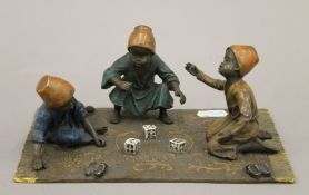 A cold painted bronze model of boys playing dice. 19.5 cm wide.