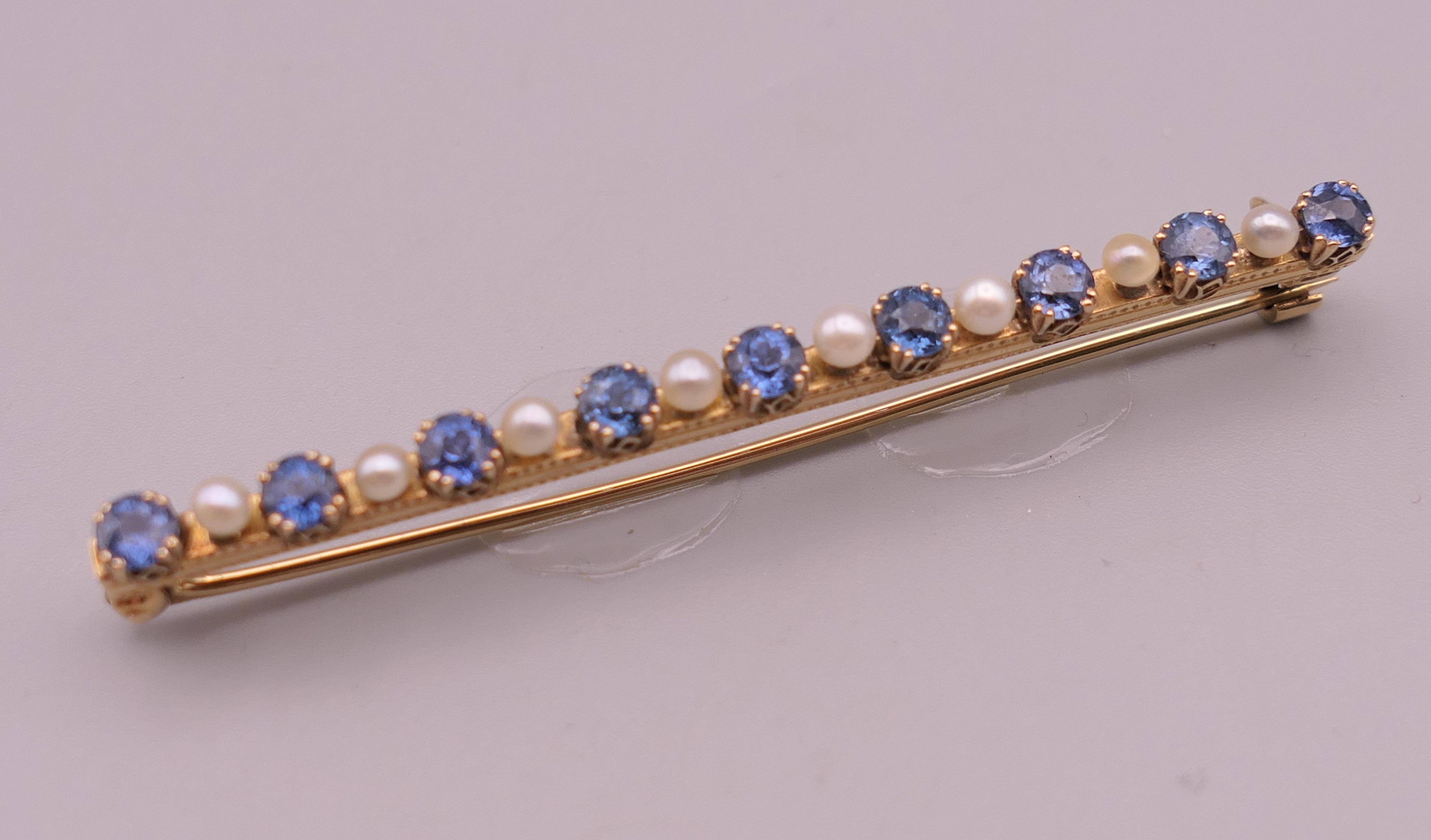 An antique natural sapphire and seed pearl unmarked gold (high carat tested) brooch, boxed.