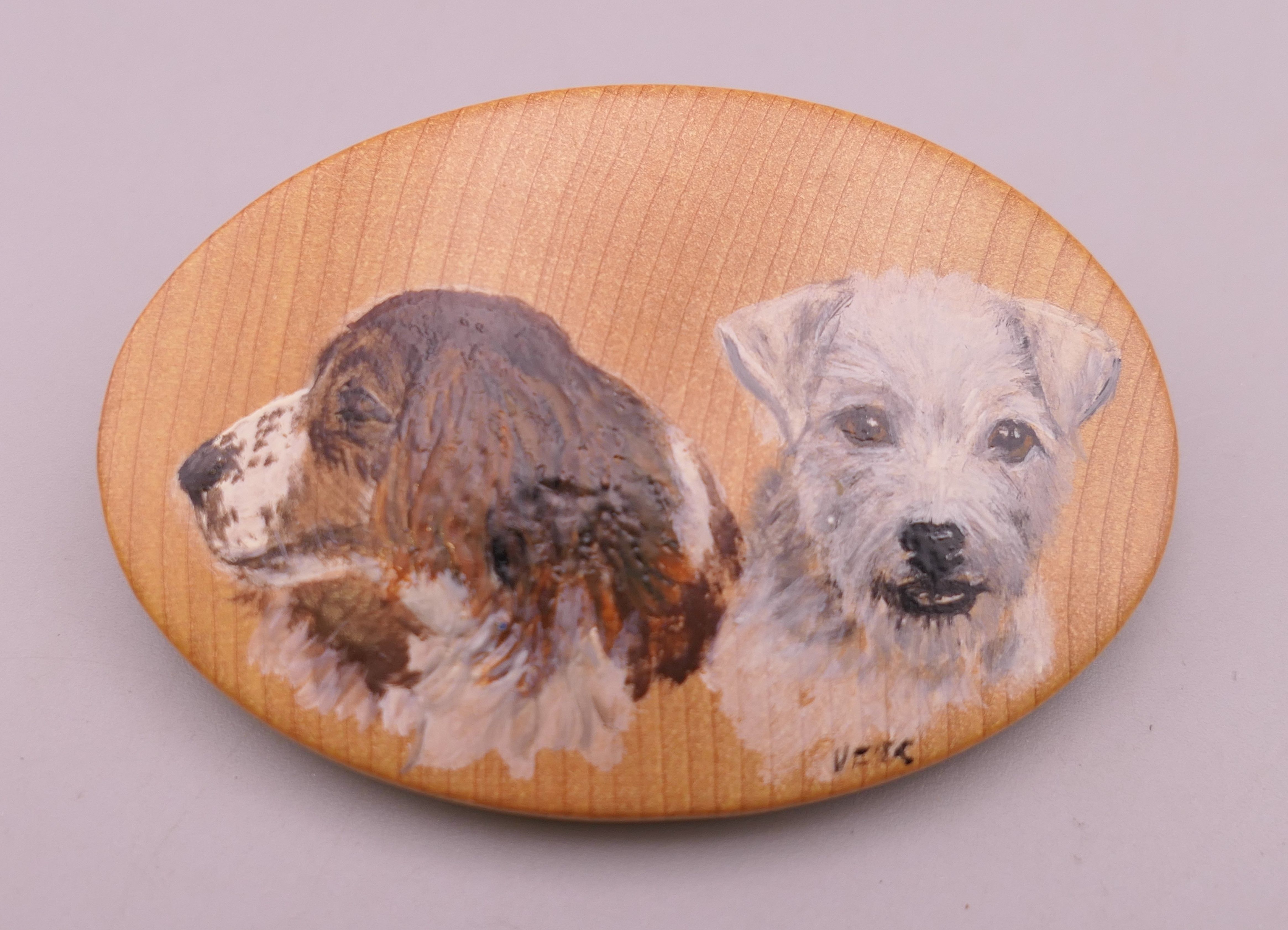 A wooden brooch painted with two dogs. 6 cm wide.