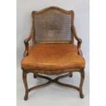 A 19th century carved caned open armchair with leather cushion. 66 cm wide.