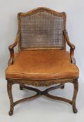 A 19th century carved caned open armchair with leather cushion. 66 cm wide.