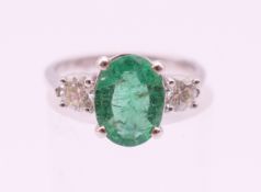An 18 ct white gold emerald and diamond trilogy ring, emerald approximately 1 carat. Ring size L.