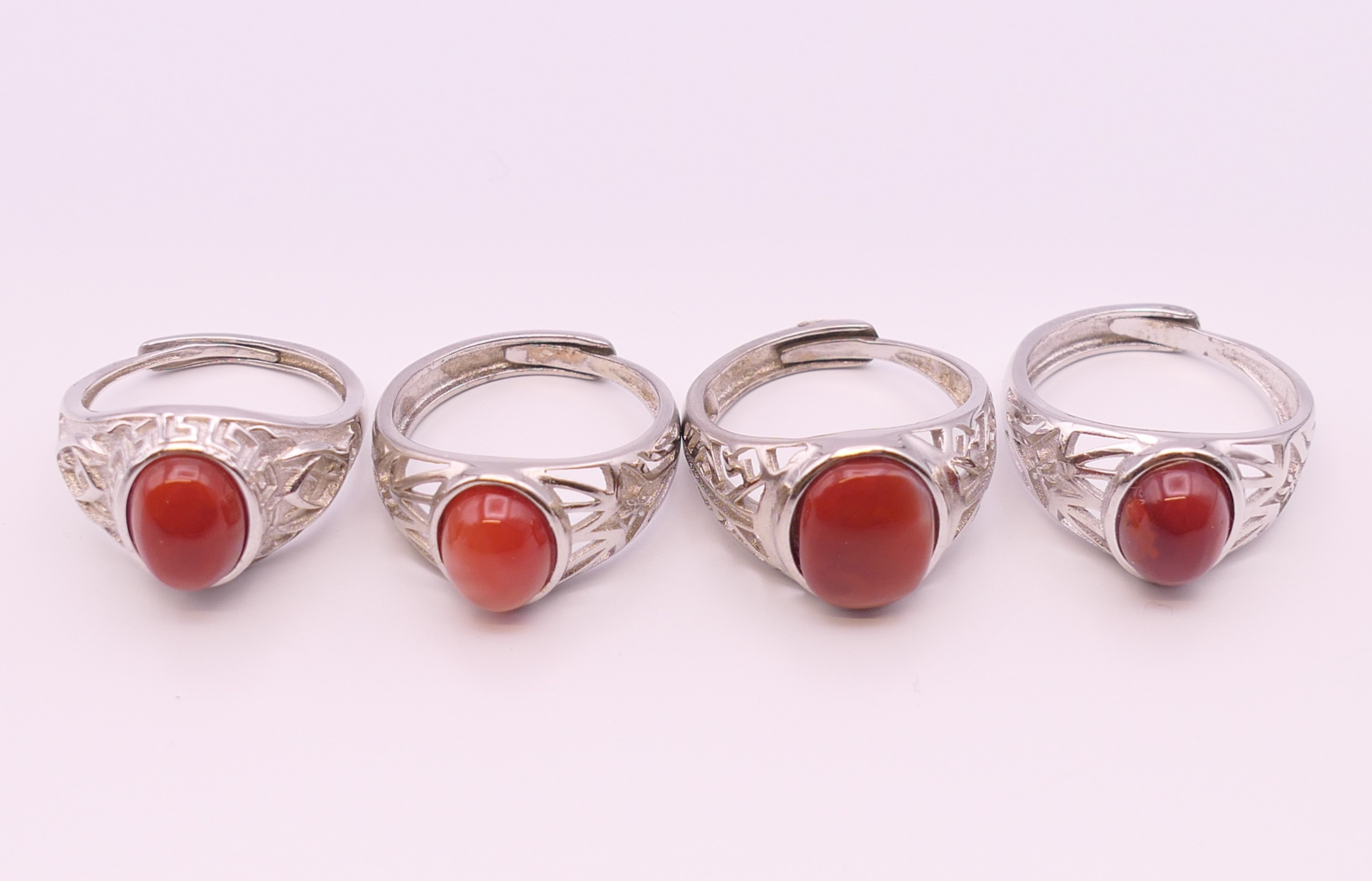 Four silver and coral rings.