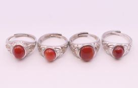 Four silver and coral rings.