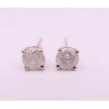 A pair of 9 ct white gold and diamond stud earrings. 0.5 cm diameter.