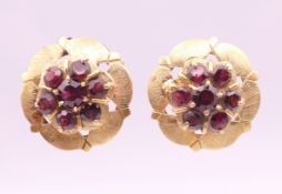 A pair of 14 ct gold garnet set flowerhead ear studs. 1.75 cm diameter. 7.7 grammes total weight.