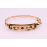 A 9 ct gold, diamond and sapphire bangle form bracelet. 6 cm internal diameter. 9.