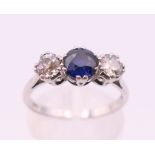 A white gold or platinum three-stone sapphire and diamond ring. Ring size O.