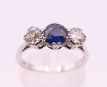 A white gold or platinum three-stone sapphire and diamond ring. Ring size O.