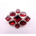 An early Victorian unmarked gold and garnet brooch, cased. 3 x 2 cm. 2.3 grammes total weight.