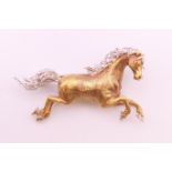 An 18 ct gold diamond set galloping horse form brooch. 4 cm long. 10.4 grammes total weight.