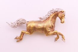 An 18 ct gold diamond set galloping horse form brooch. 4 cm long. 10.4 grammes total weight.