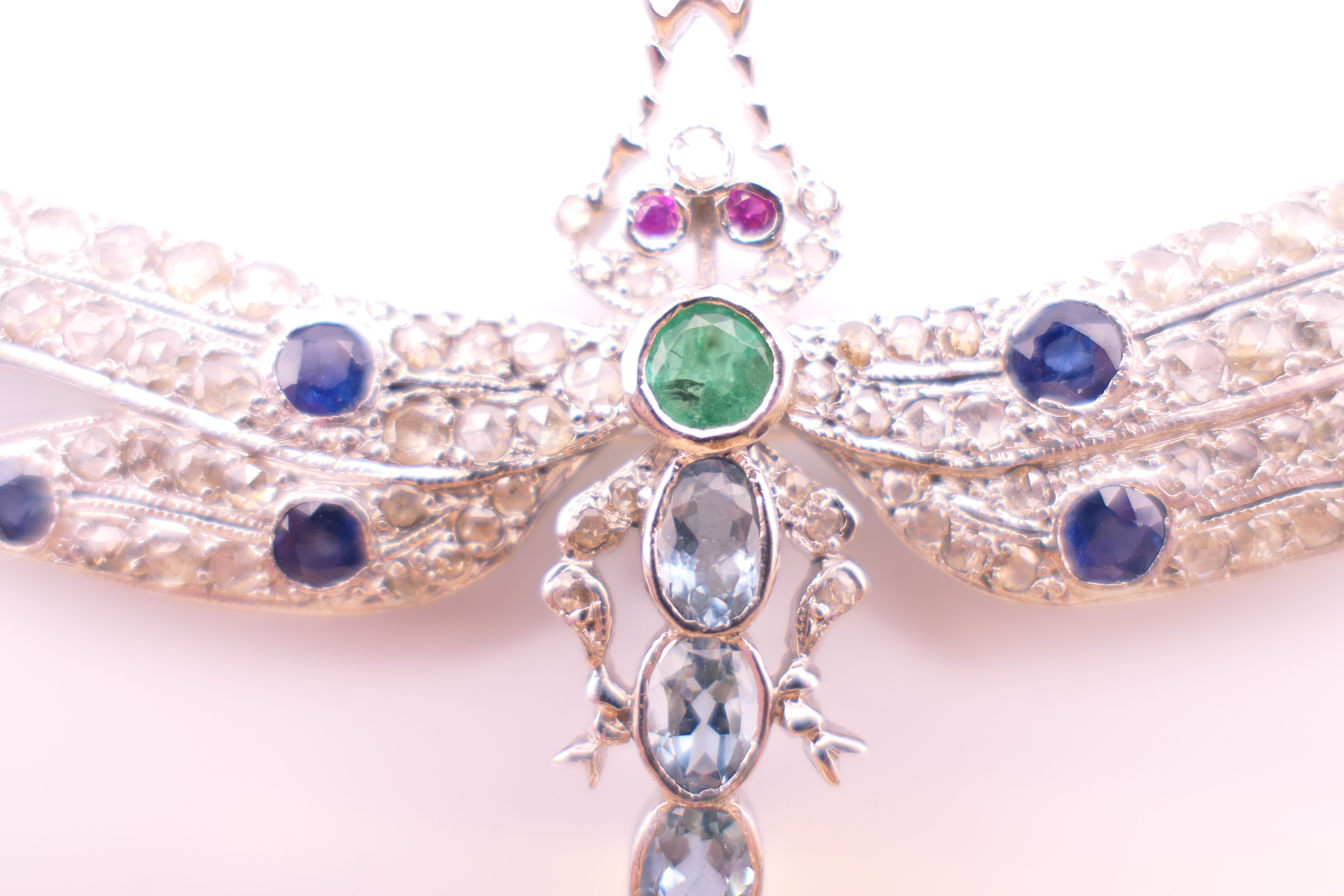 An unmarked 18 ct white gold dragonfly form diamond, sapphire, ruby, emerald and aquamarine brooch. - Image 7 of 11