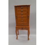 A jewellery cabinet formed as a chest of drawers on stand,