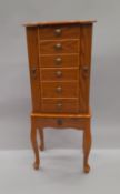 A jewellery cabinet formed as a chest of drawers on stand,