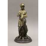 An antique sculpture in art metal of a Grecian maiden standing in front of a stool,