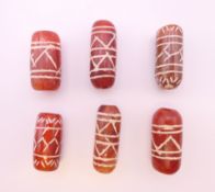 A set of six carved dzi beads. Largest 2.5 cm long.