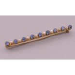 An antique unmarked gold (tested high carat) natural sapphire and seed pearl bar brooch, boxed.