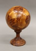 A treen model of a football on stand. 25 cm high overall.