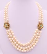 A three strand pearl necklace with 9 ct gold flowerhead clasps (strand of pearls lacking to one