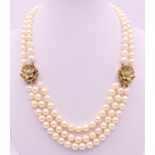 A three strand pearl necklace with 9 ct gold flowerhead clasps (strand of pearls lacking to one