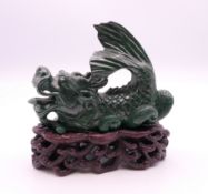 A malachite model of a dragon on a wooden base. 8.5 cm high overall, dragon 6.5 cm high.