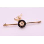 A 15 ct gold and 0.5 carat diamond set in a black circular mount mourning brooch/pin. 6 cm long. 4.