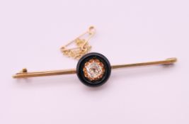 A 15 ct gold and 0.5 carat diamond set in a black circular mount mourning brooch/pin. 6 cm long. 4.