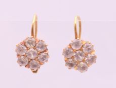 A pair of gold white sapphire earrings. 1 cm diameter.