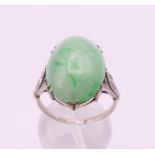 An 18 ct white gold and platinum cabochon jade and diamond ring. Ring size O/P.