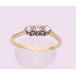 An 18 ct gold three stone diamond ring. Ring size R/S. 2.6 grammes total weight.